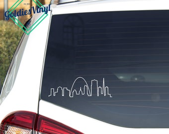 May include: White vinyl decal of the St. Louis skyline, including the Gateway Arch, on the back window of a white car.