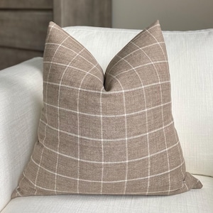 May include: A brown and white checkered throw pillow with a linen texture.