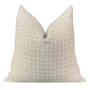 May include: A beige throw pillow with a white geometric pattern. The pillow is made of a soft, textured fabric.