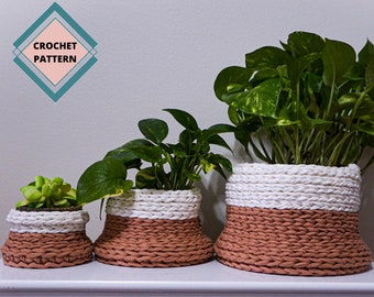 Puede incluir: Tres macetas de plantas de ganchillo en diferentes tamaños. Las macetas están hechas con hilo blanco y terracota. Las macetas están llenas de plantas.