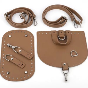 May include: A set of tan-colored purse-making components, including two shoulder straps, a base with a zipper, and a flap with a D-ring. The hardware is silver-colored. The pieces are arranged on a white background.