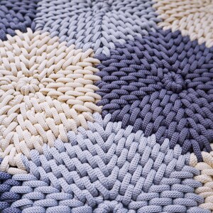 Puede incluir: Primer plano de una alfombra tejida con un patr&oacute;n circular en tonos beige, azul claro y azul oscuro.