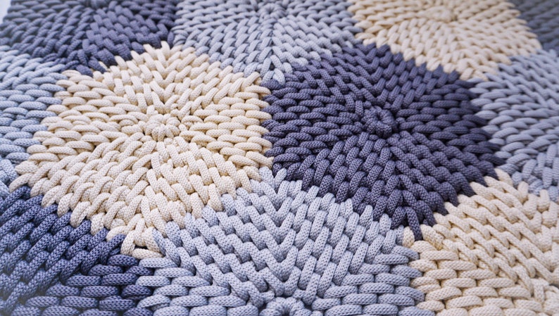 Puede incluir: Primer plano de una alfombra tejida con un patr&oacute;n circular en tonos beige, azul claro y azul oscuro.