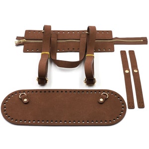 May include: Brown suede bag-making kit with a zipper, straps, and an oval base. The kit includes a zipper closure, handles, and additional straps with gold-colored hardware. The pieces are pre-punched for easy assembly.