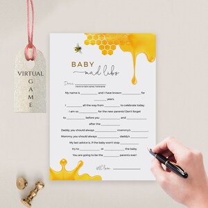 May include: A printable baby shower game card with a honeybee and honeycomb design. The card has fill-in-the-blanks for a baby mad libs game. The text on the card reads "Baby Mad Libs".