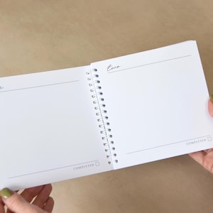 May include: Open spiral-bound notebook with blank white pages. The left page has the word "one" and a horizontal line. The right page has the word "two" and a horizontal line. The word "COMPLETED" is at the bottom of each page.