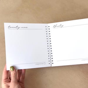 May include: Open spiral-bound notebook with blank white pages. The left page has the word "twenty-nine" and a horizontal line. The right page has the word "thirty" and a horizontal line. The word "COMPLETED" is at the bottom of each page with a checkbox.