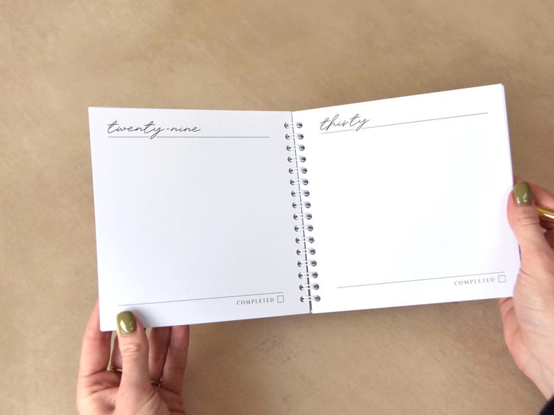 May include: Open spiral-bound notebook with blank white pages. The left page has the word "twenty-nine" and a horizontal line. The right page has the word "thirty" and a horizontal line. The word "COMPLETED" is at the bottom of each page with a checkbox.