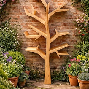 May include: A wooden tree-shaped bookshelf stands against a brick wall, surrounded by potted plants and flowers. The bookshelf has multiple shelves and branches, creating a unique storage solution. The natural wood color complements the outdoor setting.