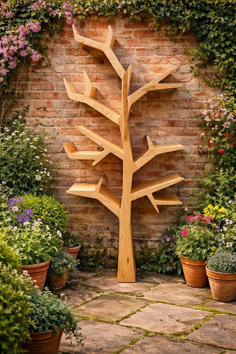 May include: A wooden tree-shaped bookshelf stands against a brick wall, surrounded by potted plants and flowers. The bookshelf has multiple shelves and branches, creating a unique storage solution. The natural wood color complements the outdoor setting.