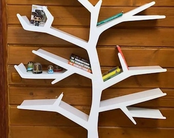 Puede incluir: Estantería blanca en forma de árbol con múltiples ramas y estantes. Los estantes están llenos de libros, figuritas y otros artículos decorativos. La estantería está montada en una pared de madera.
