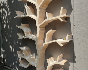 Puede incluir: Una estantería de madera con forma de árbol con múltiples ramas y estantes. La estantería está hecha de madera clara y tiene un acabado natural.