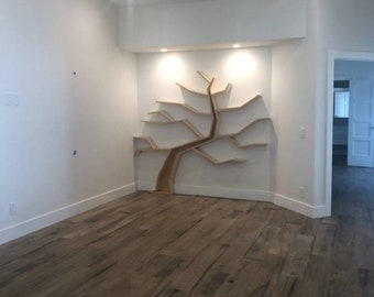 Puede incluir: Una habitación blanca con una estantería de madera en forma de árbol en la pared. La estantería tiene muchos estantes y ramas. La habitación tiene un suelo de madera.