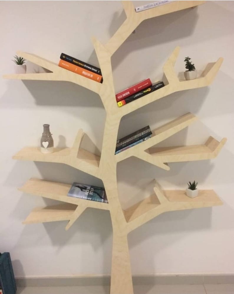 May include: A light wood bookshelf shaped like a tree with multiple branches and shelves. The shelves are filled with books and small potted plants.