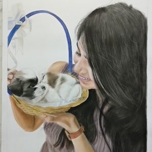Pu&ograve; includere: Una donna con lunghi capelli scuri tiene un cesto di vimini con un piccolo cucciolo bianco e marrone al suo interno. La donna sorride e guarda il cucciolo. Il cesto ha un manico blu e un nastro bianco.