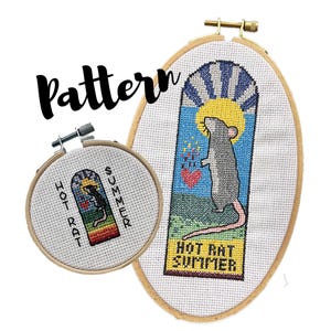 Puede incluir: Dos patrones de punto de cruz en aros de madera. El más grande presenta una rata gris con cola rosa, un sol amarillo y el texto "HOT RAT SUMMER". El más pequeño tiene el mismo diseño. La palabra "Pattern" está escrita en cursiva negra.