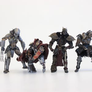 May include: Four detailed action figures of fantasy characters, including a Predator with a bladed weapon, and figures in armour. The figures are in shades of grey, brown, and red, set against a white background.