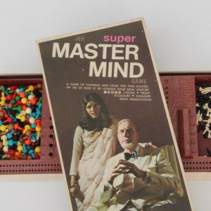May include: Vintage Master Mind board game with a brown box and lid. The box features the game title and images of two people. Inside, there are colored pegs and black and white pegs for gameplay.