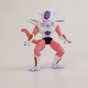 May include: A detailed figurine of a fictional character with a white, purple, and pink color scheme. The figure has a muscular build, with a tail and multiple horns. The character is wearing a black garment.