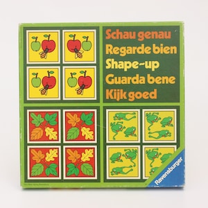 May include: A vintage board game box with a green border. The box features colorful illustrations of apples, leaves, and frogs. Text in multiple languages is displayed on the box, including "Shape-up".