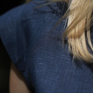 May include: Close-up of a dark blue linen fabric with a textured weave. The fabric is smooth and has a subtle sheen.