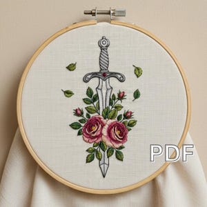 Peut inclure: Broderie d'une épée et de roses dans un cercle en bois. L'épée est argentée avec une gemme rouge, et les roses sont roses et rouges avec des feuilles vertes. Le mot "PDF" est dans le coin inférieur droit.