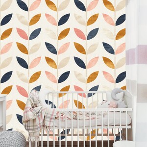 May include: A white crib with a pink and white blanket and a stuffed animal. The crib is in front of a wall with a pattern of leaves in shades of pink, blue, brown, and cream.