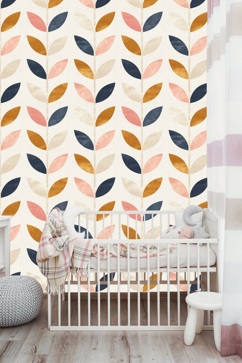 May include: A white crib with a pink and white blanket and a stuffed animal. The crib is in front of a wall with a pattern of leaves in shades of pink, blue, brown, and cream.