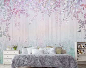 May include: A bedroom with a gray bedspread and white pillows. The wall behind the bed has a floral wallpaper with a watercolor effect. The wallpaper features purple and pink flowers and leaves.