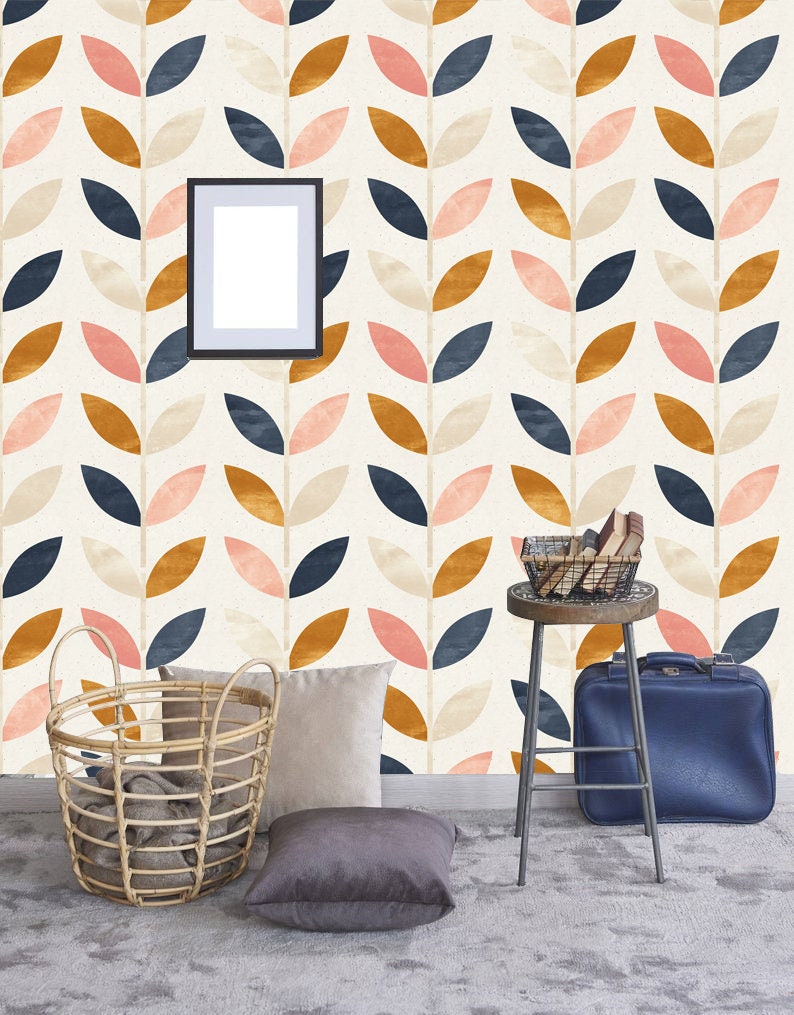 May include: A room with a white wall featuring a repeating pattern of stylized leaves in pink, blue, and gold. The wall has a framed picture, a wicker basket, a stool with a basket on top, and a blue suitcase.