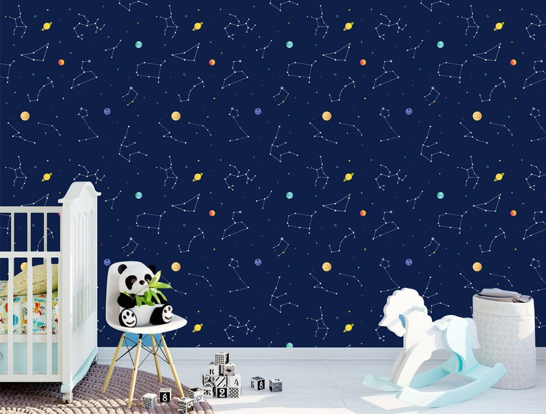 May include: Navy blue wallpaper with a constellation design, featuring white lines and colourful planets. A white cot, panda bear plush, rocking horse, and building blocks are in the foreground, suggesting a nursery theme.