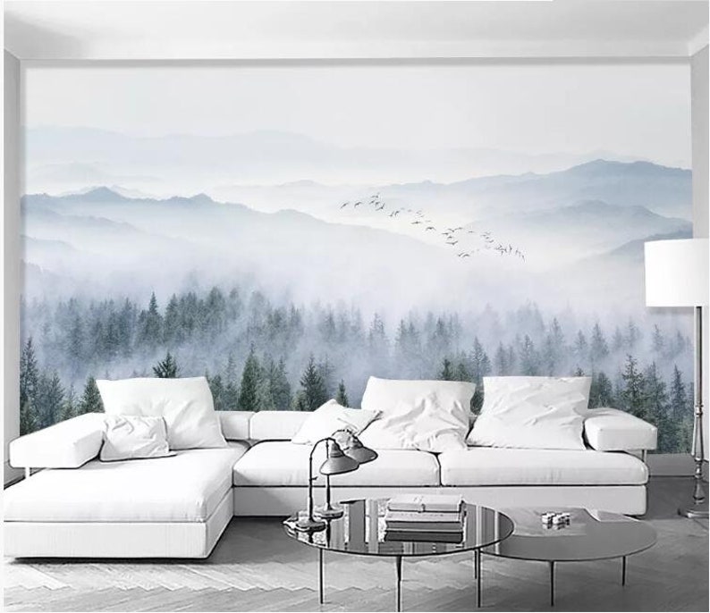 Puede incluir: Un sof&aacute; seccional blanco con un coj&iacute;n blanco se encuentra frente a un mural de pared que representa un bosque brumoso con una bandada de p&aacute;jaros volando sobre las monta&ntilde;as en el fondo.