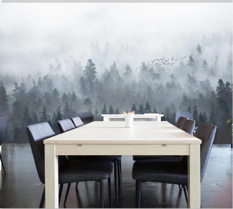 Puede incluir: Una mesa de comedor blanca con seis sillas negras frente a un fondo de bosque brumoso. El bosque est&aacute; representado en tonos de gris y blanco, con una bandada de p&aacute;jaros volando por encima.