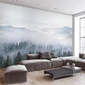 Puede incluir: Una sala de estar con un sof&aacute; seccional gris y una mesa de caf&eacute; frente a un mural de pared que representa un bosque brumoso con una cordillera en el fondo.