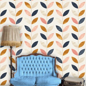 May include: A blue tufted sofa sits in front of a wall with a repeating pattern of stylized leaves in shades of pink, beige, navy blue, and gold.