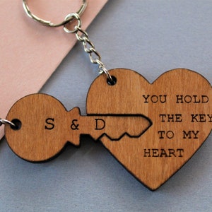 Pode incluir: Chaveiros de madeira com design de chave e cora&ccedil;&atilde;o. A chave tem as iniciais "S & D" e o cora&ccedil;&atilde;o diz "YOU HOLD THE KEY TO MY HEART". O chaveiro &eacute; preso a uma corrente e um anel prateados.