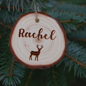 Peut inclure: Une décoration de Noël en bois avec le nom "Rachel" et une silhouette de cerf gravée dessus.