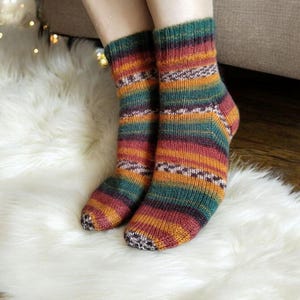 May include: A pair of colourful striped socks in shades of green, orange, red, and brown. The socks are made of a soft, knitted fabric and have a comfortable fit.