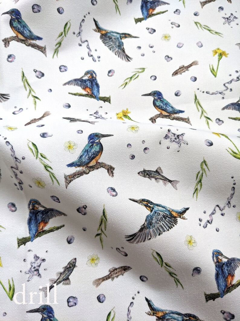 May include: White fabric with a repeating pattern of blue kingfishers, green reeds, and brown fish. The background is white with small blue dots.