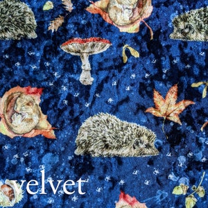 May include: Blue velvet fabric with a repeating pattern of hedgehogs, mushrooms, and autumn leaves. The fabric has a subtle texture and the word "velvet" is printed in white at the bottom of the image.
