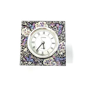 May include: Square quartz clock with a silver-tone face and Roman numerals. The clock's face is surrounded by a decorative frame with a black background and iridescent bird and floral designs. The clock reads "Yusung".