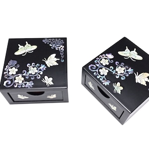 May include: Two black wooden boxes with a drawer. The boxes are decorated with a floral design and butterflies made of mother of pearl.