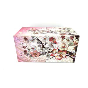 May include: A decorative box with a floral design featuring pink, red, and white blossoms on a light pink background. The box is divided into four sections and has a butterfly accent.