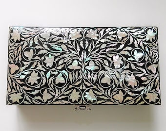 May include: Rectangular black jewelry box with a floral design inlaid with iridescent mother-of-pearl. The box features a hinged lid and a silver-colored clasp. The floral pattern includes stylized flowers and leaves.