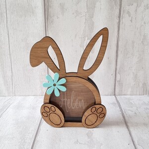 May include: Wooden bunny shaped coin bank with a blue flower and the name "Helen" engraved on the front.