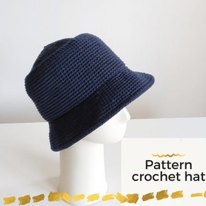 May include: A navy blue crochet bucket hat on a white mannequin head. The hat has a wide brim and a textured stitch pattern. The text "Pattern crochet hat" is visible below the hat.