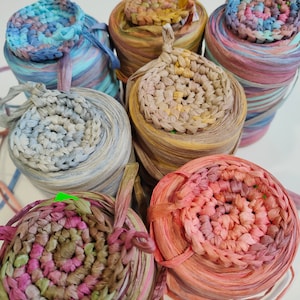 May include: Six spools of colourful paper yarn, each with a crocheted circle on top. The yarn is in shades of blue, brown, pink, and green.
