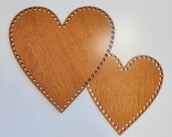 Könnte beinhalten: Zwei herzförmige Holzreifen mit Löchern an den Rändern. Die Reifen sind braun und haben eine Holzmaserung.