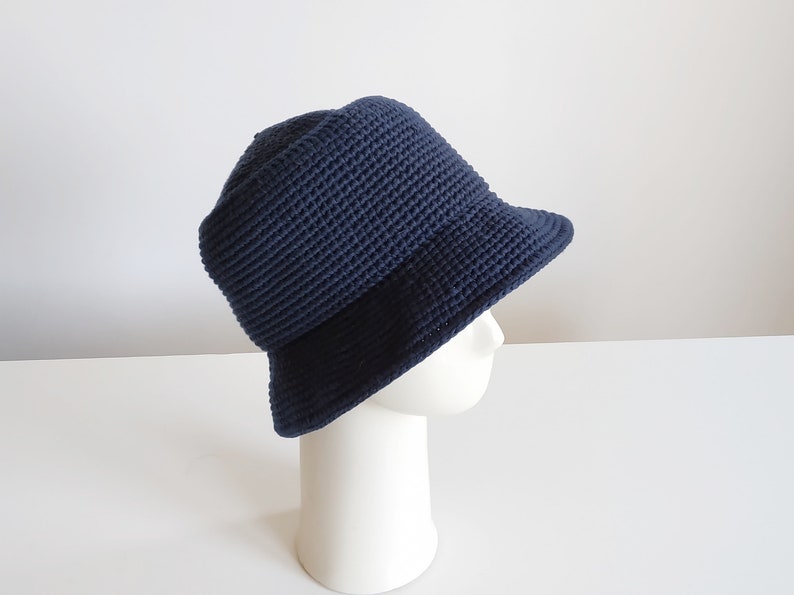 May include: A navy blue crocheted bucket hat with a wide brim.
