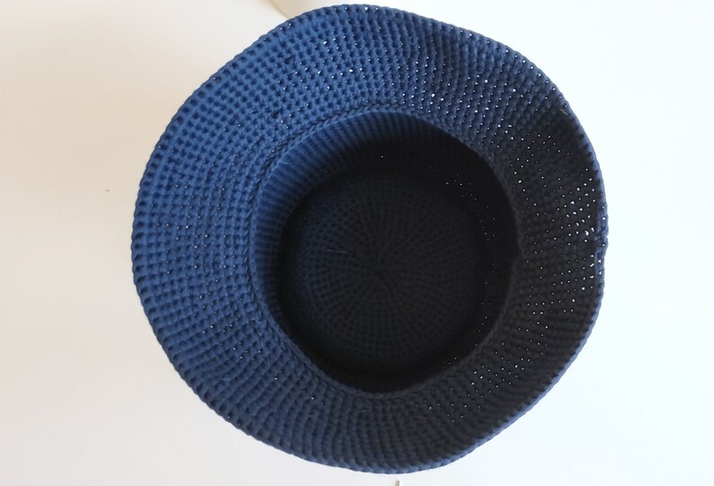 May include: A dark blue crocheted basket with a round shape. The basket is made of thick yarn and has a smooth, even texture.
